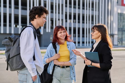 Middle aged business woman agent mentoring teacher social worker working with college university students using digital tablet outdoor