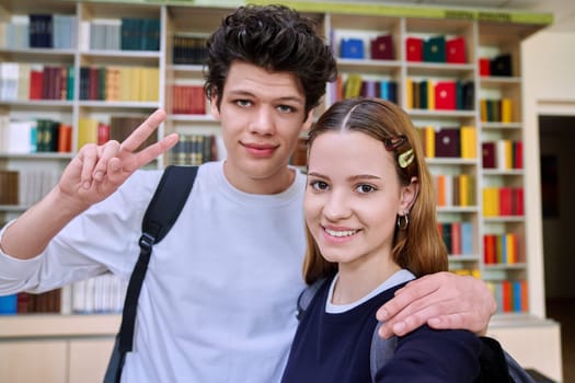 Selfie portrait of friends teenagers high school students looking at camera inside classroom. Having fun laughing teenage guy and girl in library. Friendship adolescence education lifestyle