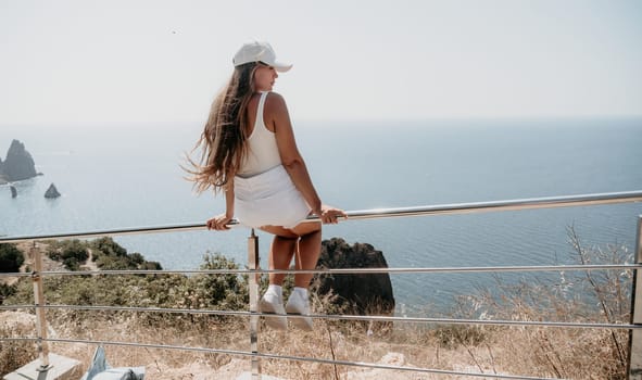 Woman travel sea. Young Happy woman in a long red dress posing on a beach near the sea on background of volcanic rocks, like in Iceland, sharing travel adventure journey