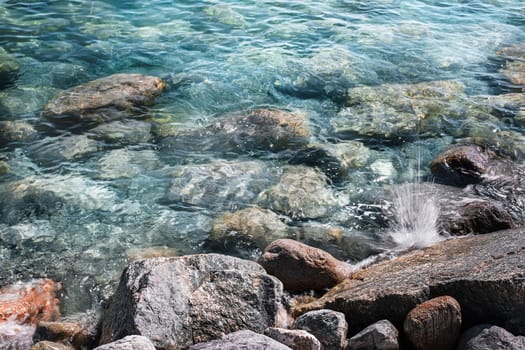 Background of clear waters against a rocky beach.