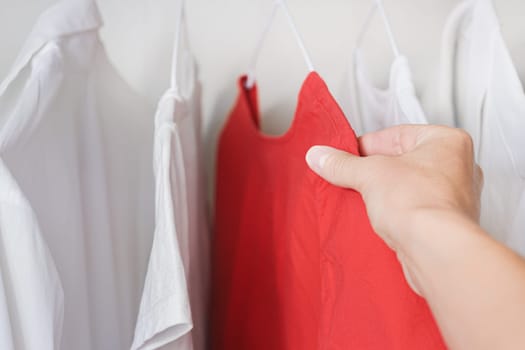 Hands of woman chooses clothes between white and red color. Choice concept.