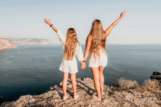 Close up portrait of mom and her teenage daughter hugging and smiling together over sunset sea view. Beautiful woman relaxing with her child.