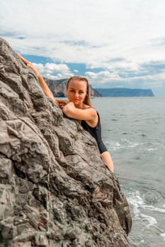 Woman swimsuit sea. Attractive blonde woman in a black swimsuit enjoying the sea air on the seashore around the rocks. Travel and vacation concept