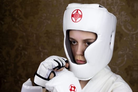 Portrait of girl in protective Kyokushin karate helmet and gloves in protective stance. Girl opponent in martial arts