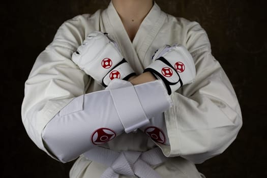 Girl in kimono and protective equipment in Kyokushin karate crossed her arms before greeting her opponent, fighting tradition of Kyokushin karate and martial arts