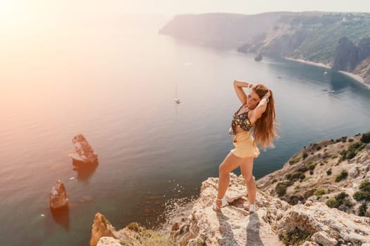 Woman travel sea. Happy tourist taking picture outdoors for memories. Woman traveler looks at the edge of the cliff on the sea bay of mountains, sharing travel adventure journey.