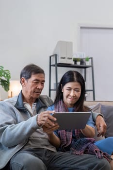 Senior couple using tablet at home. Concept of technology, companionship, and relaxation.