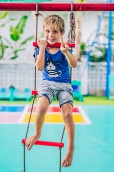 Smiling child preschool boy on rope ladder. Bright emotions. Happy childhood, enjoy life be yourself.