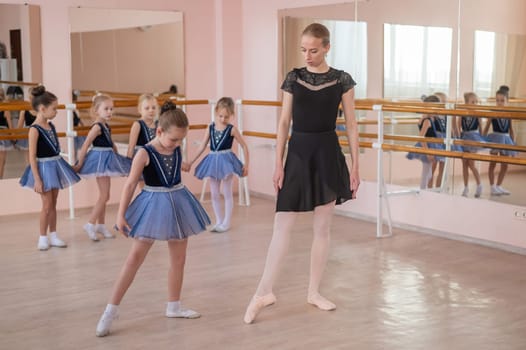 Children's ballet school. Caucasian woman teaching ballet to little girls