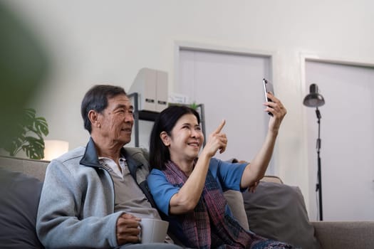 Senior couple taking selfie at home. Concept of technology, companionship, and relaxation.