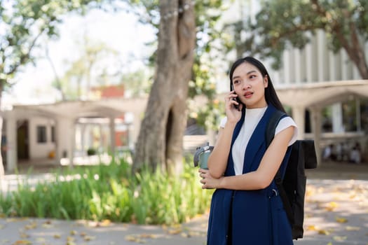 Business woman talking on smartphone while holding water bottle outdoors. Concept of professional communication, hydration, and mobile work.