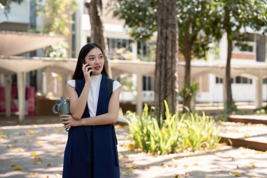 Business woman talking on smartphone while holding water bottle in park. Concept of outdoor communication, hydration, and professional lifestyle.