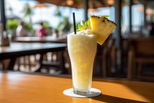 Refreshing summer coconut milk pina colada cocktail with pineapple on beach cafe table