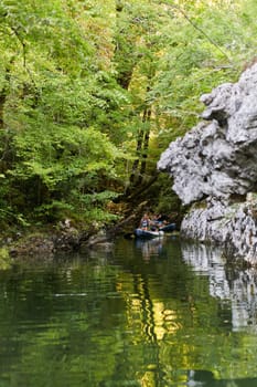 A group of friends enjoying having fun and kayaking while exploring the calm river, surrounding forest and large natural river canyons.