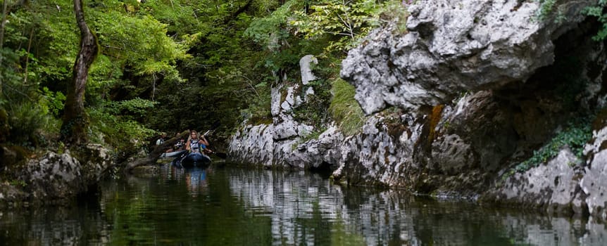 A group of friends enjoying having fun and kayaking while exploring the calm river, surrounding forest and large natural river canyons.