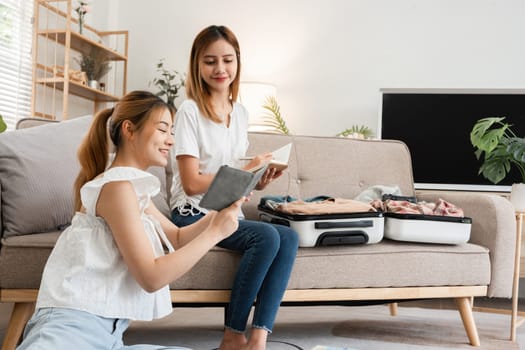 Asian women planning travel together with passport and notebook. Indoor concept of friendship and travel preparation..