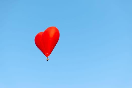vibrant red heart balloon soaring through clear blue skies, symbolizing love and freedom