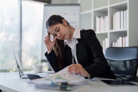 Businesswoman reviewing documents in office. Concept of stress, technology, and productivity.