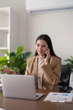 Businesswoman on phone call at desk with laptop. Concept of professional communication and office work.