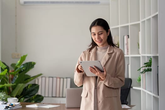 Businesswoman holding tablet and smiling in modern office. Concept of technology and professional work environment.