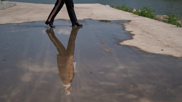 Close-up of a woman's legs walking on a large puddle