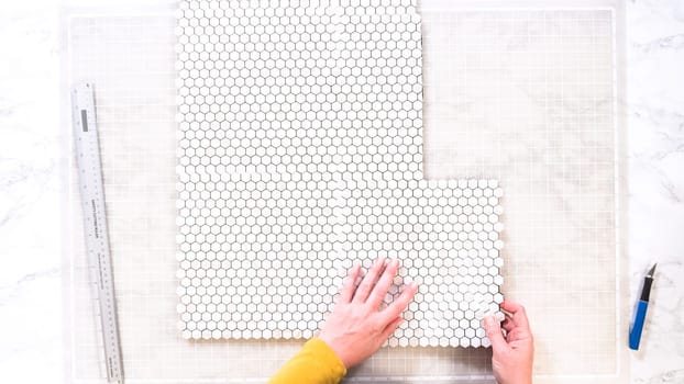 Flat lay. In the process of mounting peel and stick mosaic tiles onto a foam board, perfect for enhancing a food photography studio's aesthetic.