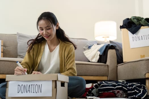 Woman preparing donation boxes at home. Concept of charity, giving, and community support.