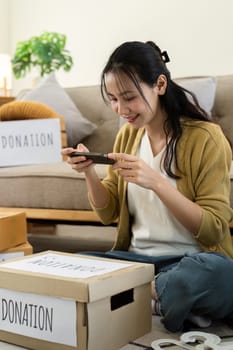 Woman taking photo of donation box at home. Concept of charity, giving, and community support.