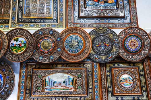 Uzbek wooden gift plates and paintings with wood carvings hand-painted traditional patterns in workshop in Uzbekistan