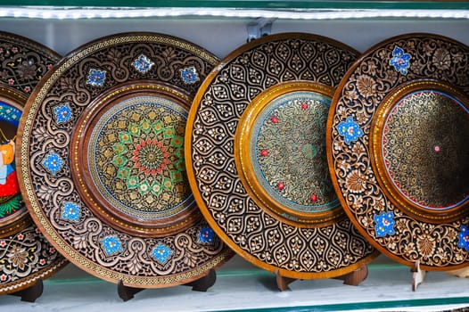 handmade Uzbek wooden souvenir plates with wood carvings hand-painted oriental patterns in bazaar of Uzbekistan in Tashkent