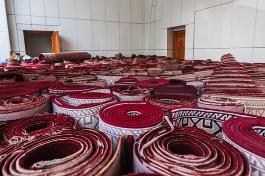 stack of rolled up traditional vintage Uzbek red carpets at oriental bazaar for sale in Tashkent in Uzbekistan