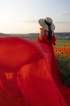 Woman poppy field red dress hat. Happy woman in a long red dress in a beautiful large poppy field. Blond stands with her back posing on a large field of red poppies