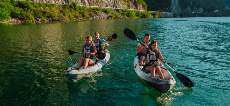 A group of friends enjoying fun and kayaking exploring the calm river, surrounding forest and large natural river canyons during an idyllic sunset