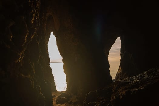 Two caves with a view of the ocean. The caves are dark and the light is coming in from the outside