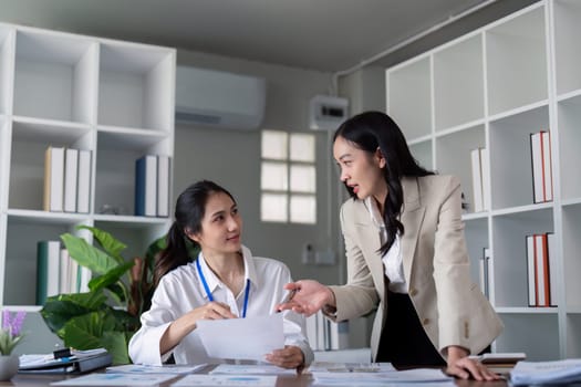 Businesswomen discussing work at office desk. Concept of collaboration, teamwork, and professional discussion.