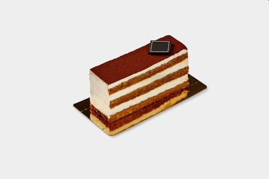 Slice of traditional Italian tiramisu cake with moist sponge layers dipped in coffee and delicate mascarpone cream, dusted with cocoa, presented on white backdrop. Confectionery art concept