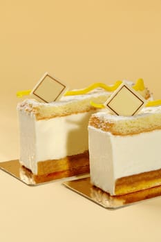 Luxurious slices of Birds Milk cake with fluffy creamy souffle, tender soft sponge base, and branded chocolate plaque, presented on warm backdrop