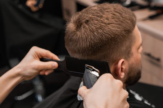 Barber skillfully shaves the clients hair on the back of the head with an electrical trimmer