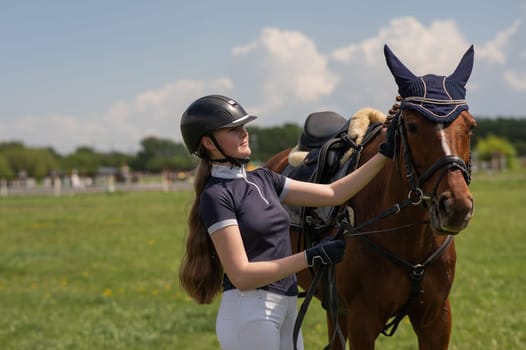 A young girl stands next to a horse before an equestrian competition