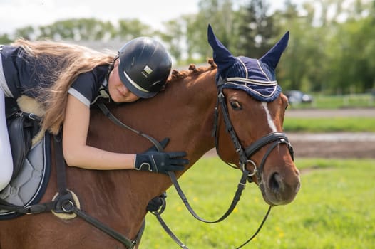Portrait of a girl jockey hugging her horse