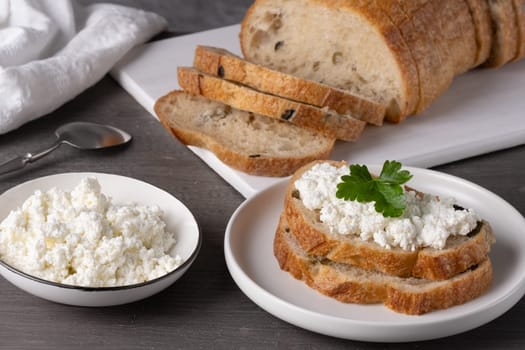 Home made bread on a wooden cutting board with curd cheese.