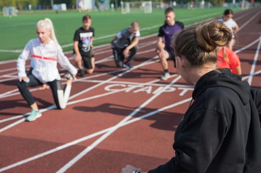 Female coach and group of children conducts a training session at the stadium. School gym trainings or athletics