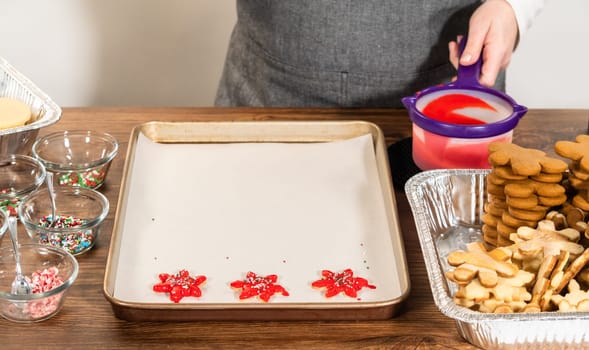 Vivid red star-shaped cookies, generously iced and speckled with green and white holiday sprinkles, freshly prepared and laid out to dry.