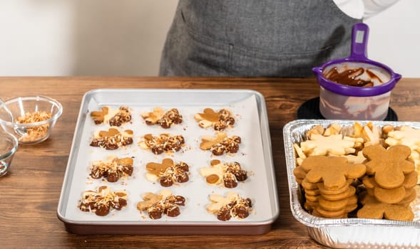 Gingerbread men cookies, chocolate-dipped feet, generously sprinkled with golden toasted coconut shavings, artfully arranged on parchment paper.