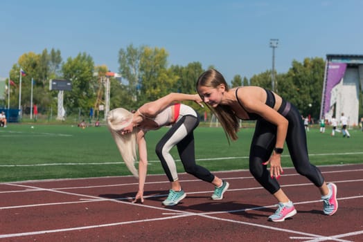 Two athlete young woman runnner on the start at the stadium outdoors