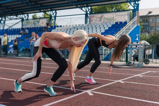 Two athlete young woman runnner on the start at the stadium outdoors