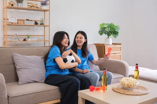 A lesbian couple cheers football and celebrate together for their favorite Euro football team. A young female couple cheers football on TV together in the living room on match day..