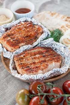 Grilled pork meat in foil with flapjack and vegetables. Summer rest concept