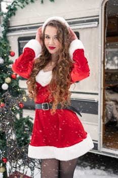 Young woman in santa costume resting at winter campsite. New year celebration concept