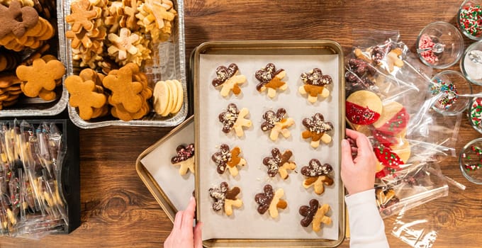 Carefully packaging Christmas cutout cookies, half-dipped in chocolate and presented in clear cellophane wrapping, perfect for festive gifting.